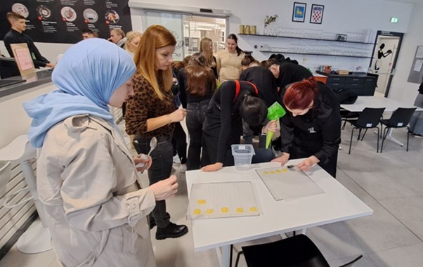 A group of people standing around a tableAI-generated content may be incorrect.